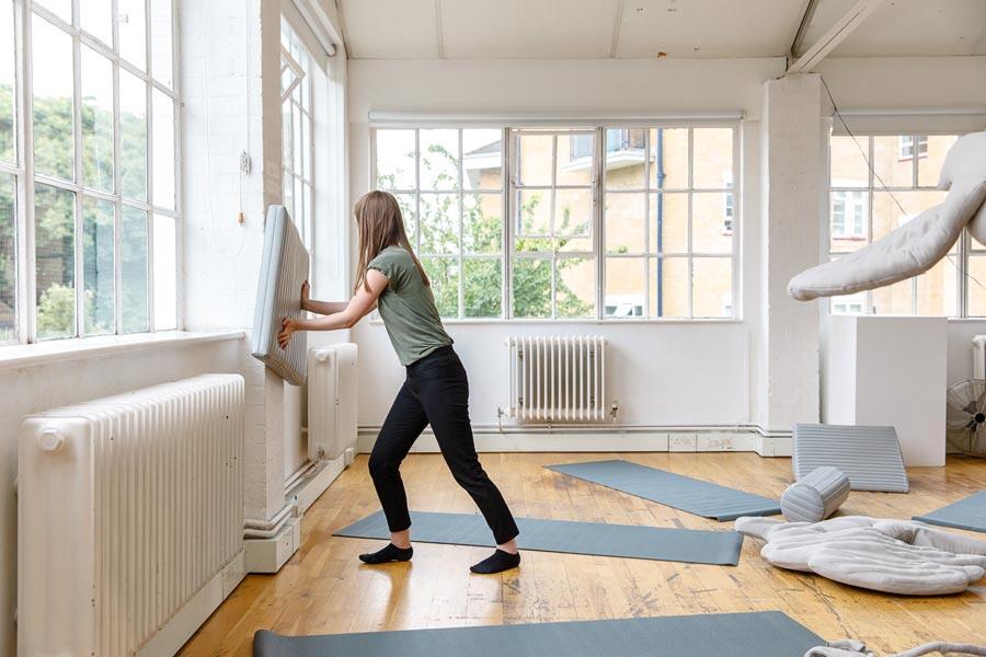 Woman pushing a pillow to the wall.